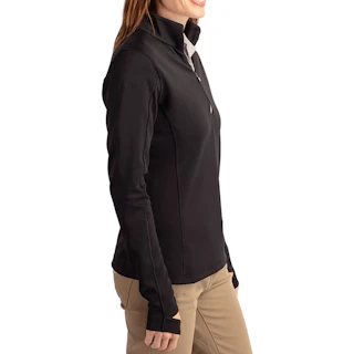 A woman standing in profile wearing a black quarter zip pullover top with khakis.