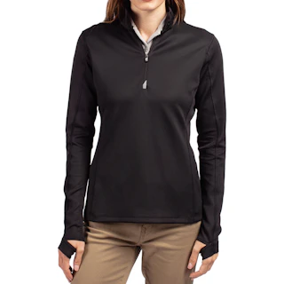 A woman standing and wearing a black quarter zip pullover with thumbholes over a polo shirt.