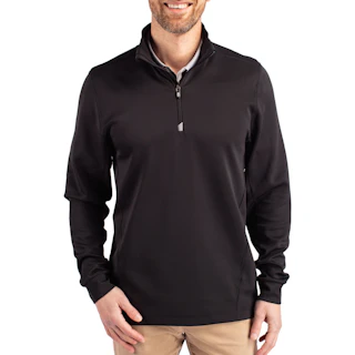 A man smiling and wearing a black quarter zip pullover over a white collar shirt with khakis.