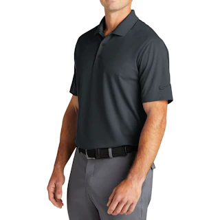 A man standing to the side wearing a dark gray Nike polo with light gray pants.