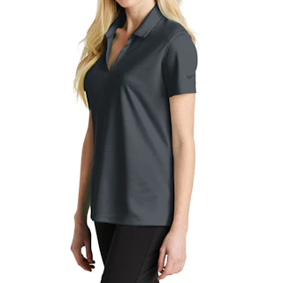 A woman standing to the side wearing a dark gray Nike polo top with black pants.