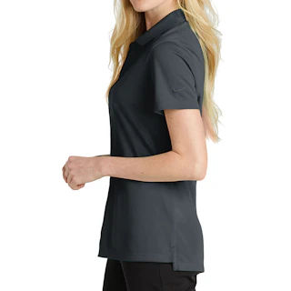A woman standing in profile wearing a solid dark gray Nike polo shirt and black pants.