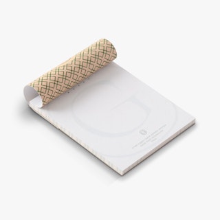 A custom notepad printed with Grandier Hotel info and a green and cream abstract design on the back.
