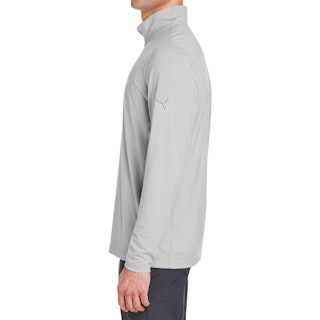 A man standing in profile wearing a Puma logo pullover in solid light gray.