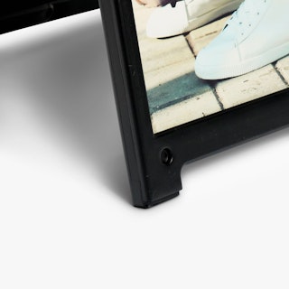 The bottom corner of a black sandwich board frame with a sign printed in cream, gray and white.