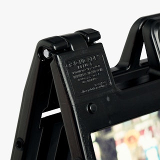 The top corner of a black A-frame sign with a print with multiple colors.