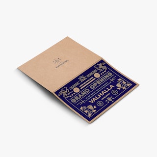 An announcement printed on Kraft paper laying open flat with a blue grand opening design on the front.