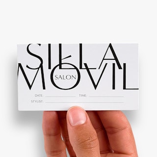 A hand holding an appointment card printed with Silla Movil Salon and a line for the date, time and stylist.