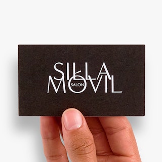 A hand holding a custom appointment card printed with a black background and Silla Movil Salon in white.