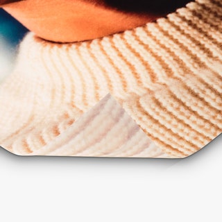 The bottom left corner of a backlit sign rolling up and custom printed with a person wearing a sweater.