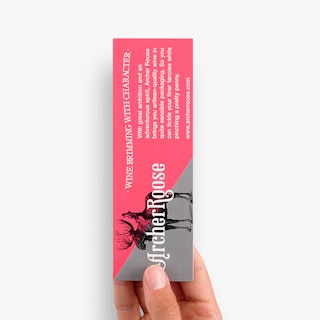 A hand holding a bookmark printed in pink and gray with a black moose graphic and Archer Roose in white.