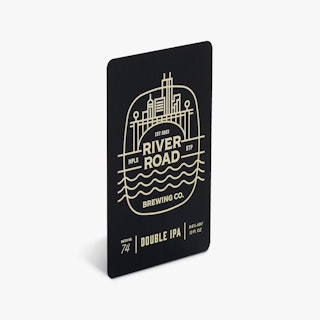 A bottle label printed with a rectangular shape, black and white design and River Road Brewing Co.