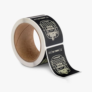 A roll of bottle labels printed with a black and white design and River Road Brewing Co.