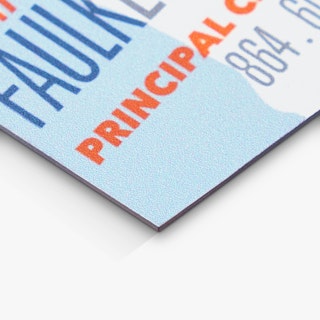 The bottom corner of a magnetic business card printed with a light blue, dark blue, orange and white design.