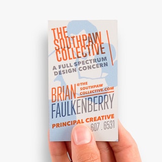 A hand holding a magnetic business card printed with a blue boxer graphic and orange text on top of it.