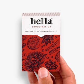 A hand holding a personalized business card printed with a red and black design and hella cocktail co.