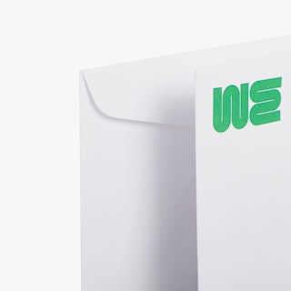 Two business envelopes overlapping each other and printed with WE in green in the top left corner.
