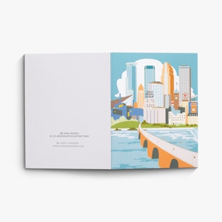 A custom card laying open flat with a graphic of downtown Minneapolis on the front and the designer's name on the back.