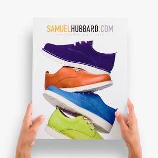 Two hands holding a cardstock sign printed with four shoes in different colors stacked on top of each other.