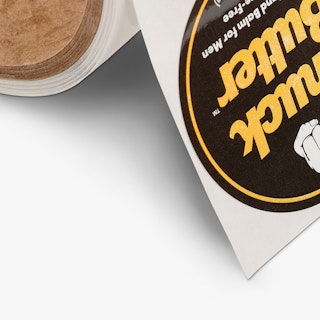 Circle roll labels printed with a yellow, white and black design and Knuck Butter in the middle.