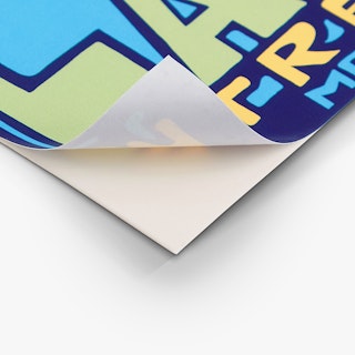 The bottom corner of a custom decal peeling off its backing with a blue, green and yellow design.