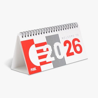 A desk calendar standing open with a red, white and black design and Welcome to 2026 printed on the cover.