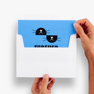 Two hands pulling a direct mail card printed with a blue and black design out of an envelope.