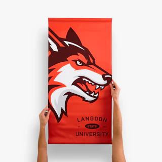Two hands holding a Langdon State University campus pole banner printed with an orange wolf design.