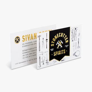 Two foil business cards printed with a black, gold foil and white design and Stonecutter Spirits on the front.