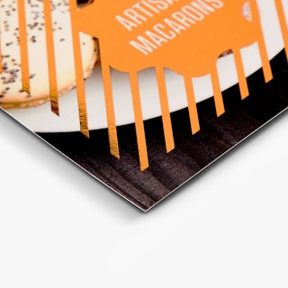 The bottom of a foil card printed with rose gold foil over an image of macarons.