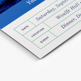 The bottom corner of a custom invitation printed with date, location and event details.