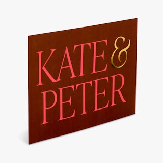 A foil wedding invitation printed with a maroon background and Kate & Peter in red and gold foil.
