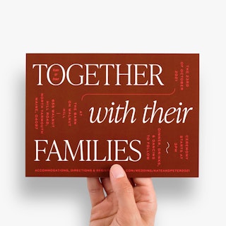 A hand holding a wedding invitation printed with Together With Their Families in white on a red background.