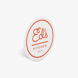 A round food label printed with a white and red design and Ed's Kitchen SLP.