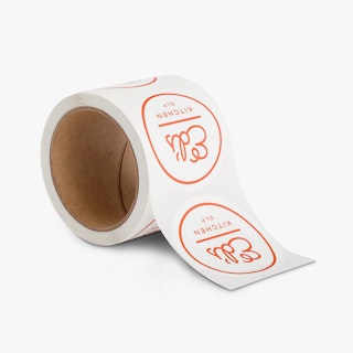 A roll of food labels printed with a round design and Ed's Kitchen SLP in white and red.