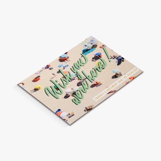 A custom greeting card laying closed with Wish You Were Here and an image of people laying on the beach.