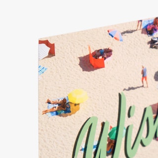 The top corner of a greeting card printed with an image of people laying on the beach and green lettering.
