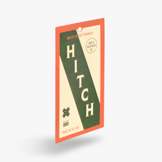 An apparel hang tag printed with Hitch branding in green, cream and orange and one drill hole.