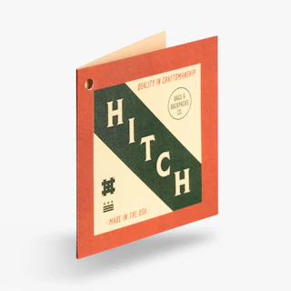 A square hang tag printed with a Hitch design in green and orange and one drill hole.