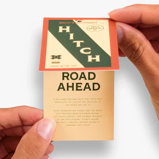 Two hands opening up a custom printed hang tag with Hitch marketing and information.