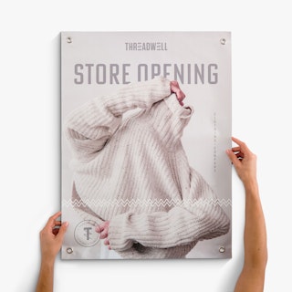 Two hands holding a hanging banner custom printed with Threadwell Store Opening in cream and gray.