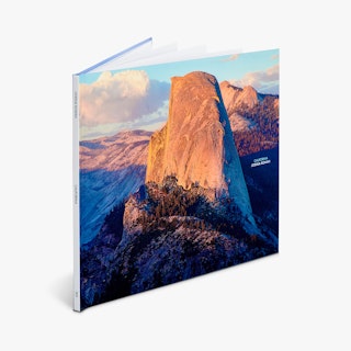 A hardcover photography book standing open with a mountainous landscape printed on the front.