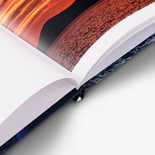 The spine of a hardcover book laying open to nature photography.