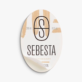 An oval product label peeling off its backing and printed with a black and tan design.