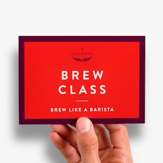 A hand holding a custom invite printed with a maroon and red design and Brew Class in white.