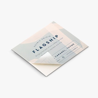 A custom label with the bottom corner peeling off its backing and printed with coffee bean details.