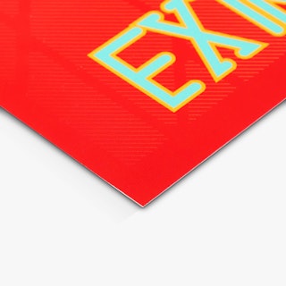 The bottom corner of a large poster printed with a bright red background and blue and yellow letters.