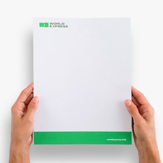 Two hands holding a custom letterhead printed with a white and green design and World Express in the corner.