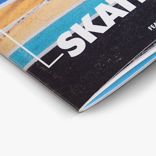 The bottom corner of a magazine printed with a saddle stitch binding and a black, blue and yellow cover design.