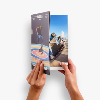 Two hands holding open a custom magazine printed with skateboarding imagery on the cover and inside pages.
